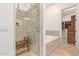 Well-lit bathroom featuring a walk-in shower with a bench and a soaking tub, leading to a walk-in closet at 8689 E Krail St, Scottsdale, AZ 85250