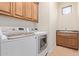 Bright laundry room with front load washer and dryer, custom cabinets, and a utility sink at 8689 E Krail St, Scottsdale, AZ 85250