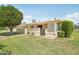 View of grassy backyard with mature tree and partial view of home's exterior with covered patio at 9802 N Balboa Dr, Sun City, AZ 85351
