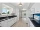 Modern kitchen with white cabinetry, dark countertops, a double sink, and tiled flooring, offering style and functionality at 9802 N Balboa Dr, Sun City, AZ 85351
