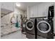 Well-equipped laundry room with washer, dryer, utility sink, and ample storage in white cabinetry at 9921 E Doubletree Ranch Rd, Scottsdale, AZ 85258