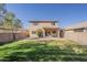Backyard of a two-story home featuring a grass lawn, block wall, and desert landscaping at 9939 W Southgate Ave, Tolleson, AZ 85353