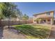 Backyard of a two-story home featuring a grass lawn, block wall, and desert landscaping at 9939 W Southgate Ave, Tolleson, AZ 85353