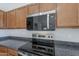 Close up of a kitchen featuring stainless steel appliances, granite countertops, and wood cabinets for a modern look at 9939 W Southgate Ave, Tolleson, AZ 85353