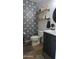 This stylish bathroom features unique patterned tiles, floating shelves, and a sleek black vanity, with creative wall design at 10036 W Chipman Rd, Tolleson, AZ 85353