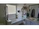 This bright bathroom is designed with a relaxing soaking tub, a vanity with a mirror, and elegant decor at 10036 W Chipman Rd, Tolleson, AZ 85353