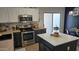 This kitchen showcases a stainless steel oven, microwave and an island, adjacent to a dining table and sliding doors at 10036 W Chipman Rd, Tolleson, AZ 85353