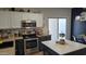 Modern kitchen with stainless steel appliances, contrasting cabinetry, and an island adjacent to a dining table and sliding doors at 10036 W Chipman Rd, Tolleson, AZ 85353
