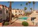 Exterior view of a community pool with lounge chairs, mature landscaping, and nearby residential buildings at 12123 W Bell Rd # 211, Surprise, AZ 85378