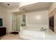 Bright bathroom featuring a glass shower, soaking tub, tile surround fireplace and neutral color palette at 13324 W Annika Dr, Litchfield Park, AZ 85340