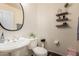 Powder room featuring a round mirror, decorative shelves, and an elegant pedestal sink at 13324 W Annika Dr, Litchfield Park, AZ 85340