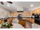 Well-lit kitchen with wooden cabinets, an island cooktop, stainless steel appliances, and an adjacent dining area at 13324 W Annika Dr, Litchfield Park, AZ 85340