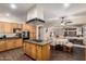 Open kitchen with wooden cabinets, an island cooktop, stainless steel appliances, and access to the living area at 13324 W Annika Dr, Litchfield Park, AZ 85340