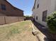 A well-maintained backyard features a green lawn and rock landscaping. The yard is separated by a block wall at 16784 W Polk St, Goodyear, AZ 85338