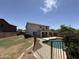 Backyard oasis featuring a lush lawn, refreshing pool, and a charming two-story home at 16784 W Polk St, Goodyear, AZ 85338