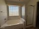 Bathroom features an soaking tub with glass block window and separate glass enclosed shower at 16784 W Polk St, Goodyear, AZ 85338