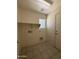 Functional laundry room featuring tile flooring, window and practical shelving for storage at 16784 W Polk St, Goodyear, AZ 85338