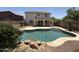 Inviting backyard featuring a sparkling pool with rock accents and a well-maintained two-story house at 16784 W Polk St, Goodyear, AZ 85338