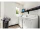 A bright laundry room with white washer and dryer and a dark floating shelf at 1700 S Martingale Rd, Gilbert, AZ 85295