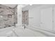 Modern bathroom featuring marble wall tile, bathtub, and quartz vanity at 25726 W Burgess Ln, Buckeye, AZ 85326