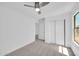 Bright bedroom features neutral carpet, ceiling fan, closet, and natural light from the window at 25726 W Burgess Ln, Buckeye, AZ 85326