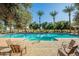 A stunning community pool is surrounded by lush greenery, lounge chairs, and palm trees at 3037 E Hobart St, Gilbert, AZ 85296