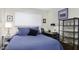 Cozy bedroom with blue quilted bedspread, a small desk, and shelving unit with glassware on display at 310 W Earll Dr # 102, Phoenix, AZ 85013