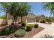 Inviting home showcasing desert landscaping, lush green bushes and convenient driveway in quiet community at 40066 W Jenna Ln, Maricopa, AZ 85138