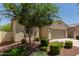Single-story home with tidy landscaping, including green bushes and desert rock for a low-maintenance yard at 40066 W Jenna Ln, Maricopa, AZ 85138