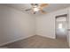 Neutral carpeted bedroom featuring a ceiling fan, natural light, and a doorway to another room at 41767 W Somerset Dr, Maricopa, AZ 85138