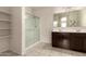 Well-lit bathroom with a glass-enclosed shower, dual sinks, and ample storage shelves at 5039 S 237Th Ln, Buckeye, AZ 85326