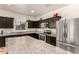 Well-equipped kitchen featuring stainless steel appliances, granite countertops, and stylish dark wood cabinetry at 5039 S 237Th Ln, Buckeye, AZ 85326