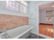 Classic clawfoot tub with exposed brick accent wall and window at 711 E Mckinley St, Phoenix, AZ 85006