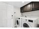 Functional laundry room with white washer, dryer, and dark-toned cabinets for ample storage at 8361 E San Rafael Dr, Scottsdale, AZ 85258