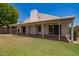 Expansive backyard featuring a covered patio, lush lawn, and a light colored home with a chimney at 10845 W Manzanita Dr, Peoria, AZ 85345