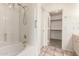 Bright bathroom showcasing a shower-over-tub with white tiling and a walk-in closet featuring shelving at 10845 W Manzanita Dr, Peoria, AZ 85345