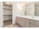 Light bathroom with a double sink vanity, a large mirror, and a walk-in closet with multiple racks at 10845 W Manzanita Dr, Peoria, AZ 85345