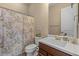 Well-lit bathroom featuring a white sink, brown cabinets, and a shower with a leaf-patterned curtain at 10914 E Tarragon Ave, Mesa, AZ 85212