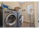 Modern laundry room with front-load washer and dryer, wooden floors, and shelving at 10914 E Tarragon Ave, Mesa, AZ 85212