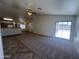 Carpeted living room with open floorplan looking towards a kitchen and sliding glass door at 13004 W Saint Moritz Ln, El Mirage, AZ 85335