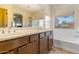 Bright bathroom featuring double vanity, tub, and natural light from two windows at 16559 W Lincoln St, Goodyear, AZ 85338