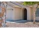 Close-up of the front entrance with an arched entryway, stucco facade, and a two car garage at 1718 E Harwell Rd, Phoenix, AZ 85042