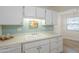 The kitchen features white cabinets, neutral countertops, a stainless steel sink, and a view to the breakfast nook at 17441 N Del Webb Blvd, Sun City, AZ 85373