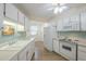 Well-lit kitchen showcasing white cabinets, appliances, and a double basin sink with views to the breakfast nook at 17441 N Del Webb Blvd, Sun City, AZ 85373