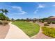 Walking path through neighborhood park with lush green grass and colorful landscaping at 17664 W Marshall Ln, Surprise, AZ 85388