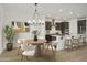 Open-concept dining area with stylish chandelier, flowing into a modern kitchen with an island and stainless hood at 19028 W Rose Ln, Waddell, AZ 85355