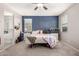 A cozy bedroom featuring a striking navy accent wall, carpet floors, and natural light from the window at 2176 W Larissa Ln, San Tan Valley, AZ 85144