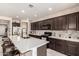 A spacious kitchen featuring dark cabinets, a center island with seating, and stainless steel appliances at 2176 W Larissa Ln, San Tan Valley, AZ 85144