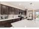 Bright kitchen boasts dark wood cabinets, stainless appliances, and a white countertop center island with black faucet at 2176 W Larissa Ln, San Tan Valley, AZ 85144