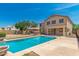 This backyard offers a pool with a stone border, an outdoor kitchen, and outdoor lighting at 26272 N 73Rd Dr, Peoria, AZ 85383